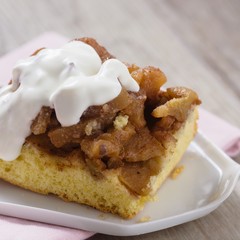 Apple crumble pie served on white plate on white wooden table