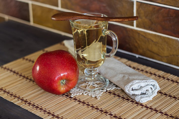 Fresh apple, drink fresh apple and a wooden spoon on a background of a brick wall. Selective focus.
