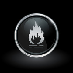 Flammable fire symbol with flame icon inside round chrome silver and black button emblem on black background. Vector illustration.