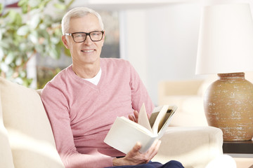 Enjoy a good book. Shot of an senior man relaxing at home and reading a book.