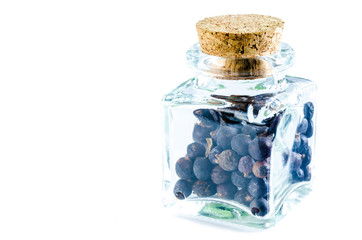 Dry juniper berries in glass bottle isolated on white background. Closeup macro shot.