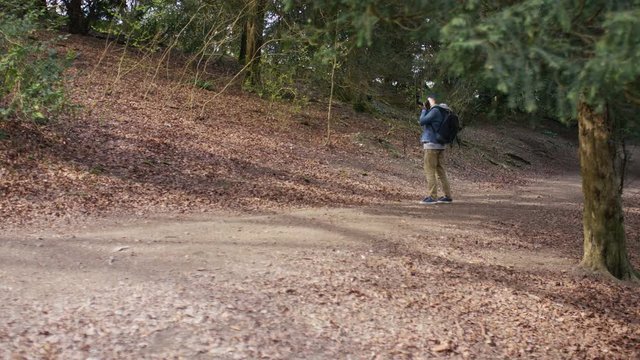 4K Wide angle shot of photographer walking in the forest taking photos