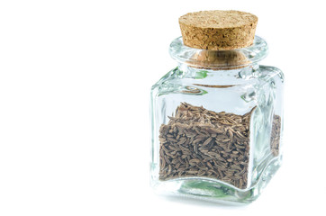 Dry caraway seeds in glass bottle isolated on white background. Closeup macro shot.