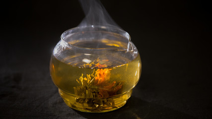Green Chinese tea flower bud blooming in glass teapot.