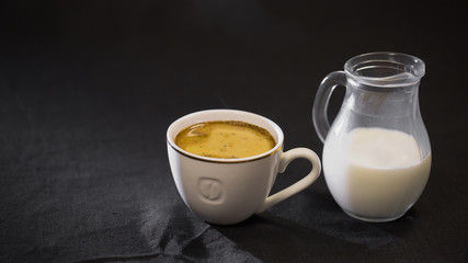 coffee in a white Cup milk in a small jug on black background.