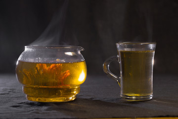 Chinese green tea Bud blooms in a glass teapot. A Cup of tea on a black background.