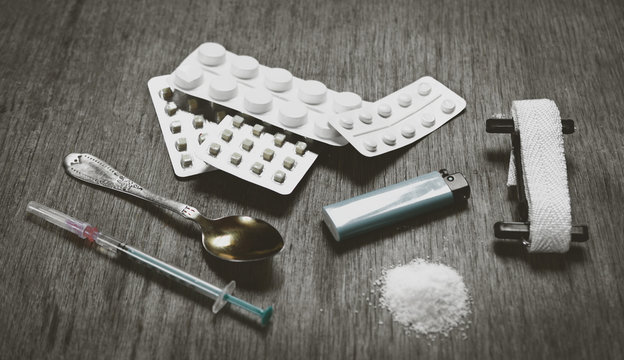 set addict: pills, heroin or cocaine, syringe, spoon, lighter and burn on the table