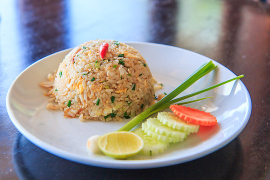 Fried rice in Thai style. Lemon, Cucumber, Carrot, and Spring onion are dish sides.