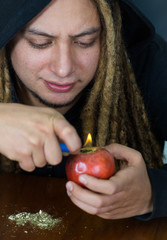 Man creating an apple bong using knife and a plastic tube, drug addiction concept, marijuana lying...