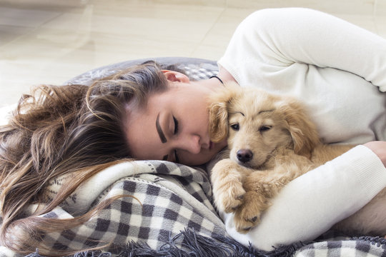 young pretty girl sleeps with puppy on the blanket