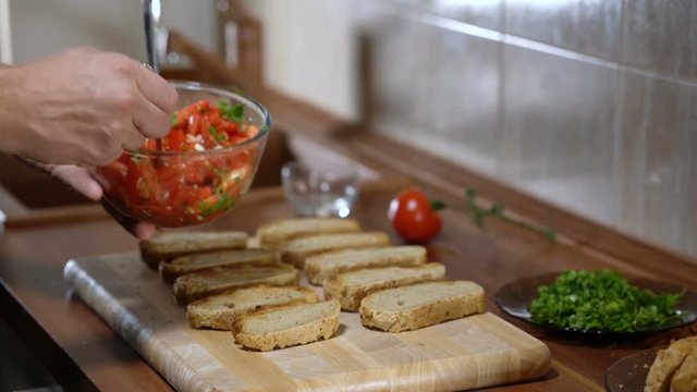 The person puts the ingredients on top of the bread for cooking bruschetta