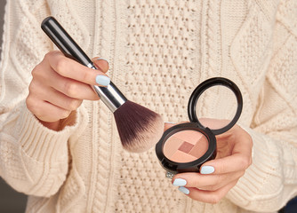 Beautiful brush and blush in well-groomed female hands.