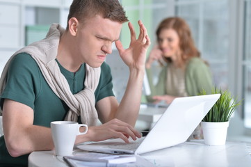 Young man working in office with a laptop