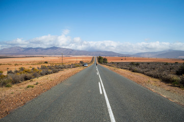 Woman on the Highway – South African Landscape with Mountains, Bushes, Plains and Road