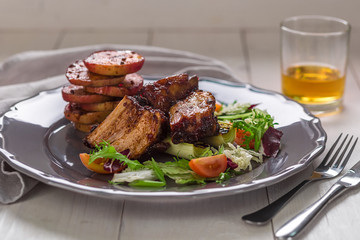 Hot Meat Dishes. Pork ribs grilled with salad and apples on a plate.