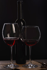 wineglasses with bottle, corkscrew on wooden table with sackcloth napkin