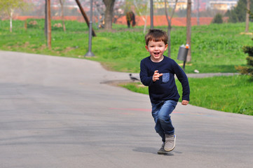 Fototapeta na wymiar Happy boy play and running at park in spring. Little smiling kid play in city park.