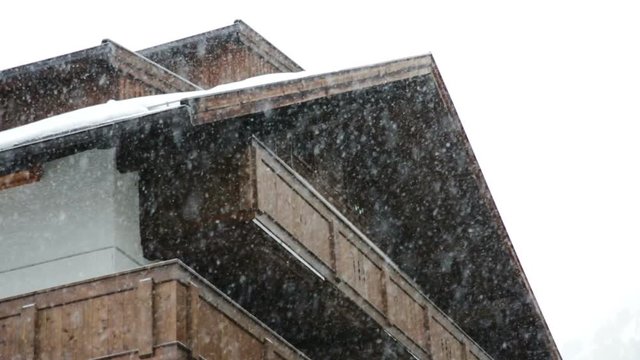 Low angle view of heavy snow falling outside a dark wooden ski chalet in Obergurgl, Austria