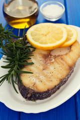 grilled fish with lemon in white dish on wooden background