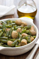green beans with mushrooms in dish on wooden background
