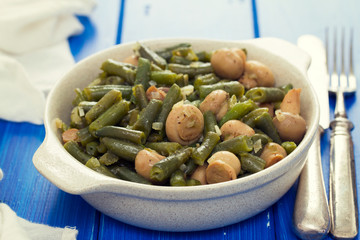 green beans with mushrooms in dish on wooden background