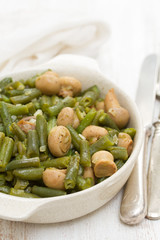 green beans with mushrooms in dish on wooden background