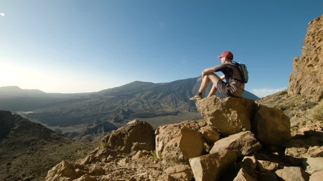 Mountain Hiking. Young Man Sitting on a Rock