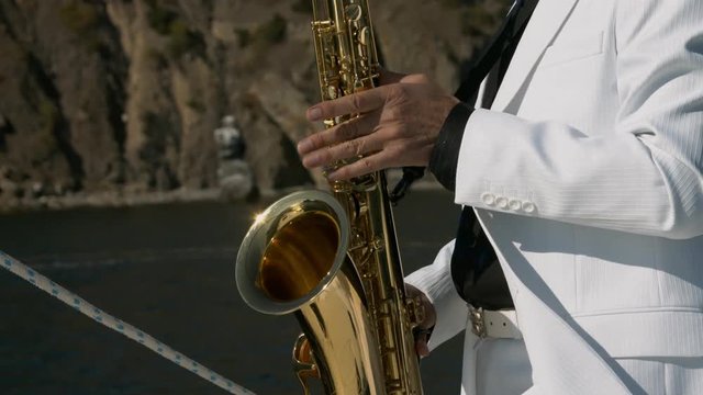 Musician is playing on saxophone at white yacht