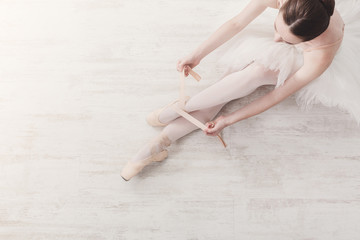 Ballerina puts on pointe ballet shoes, graceful legs © Prostock-studio