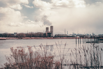 Obraz premium Power plant energy silos. Industrial energy smoke stacks. Dried up low tide lake with mud bank. Swamp waterfront bay area. Industrial design and infrastructure. Architectural detail. Isolated plant.