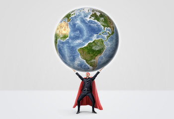 A smiling businessman in superhero red cape with hands raised in success motion holding a globe on white background.