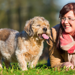 young woman lies with her dog in the grass