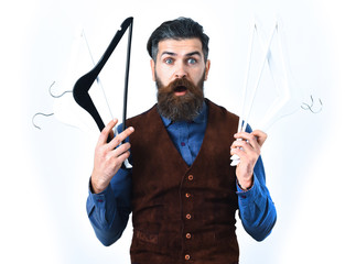 bearded man holding clothes racks with surprised face