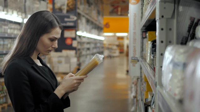 Woman choosing spaghetti italian pasta in grocery store. Brunette shopping in food supermarket