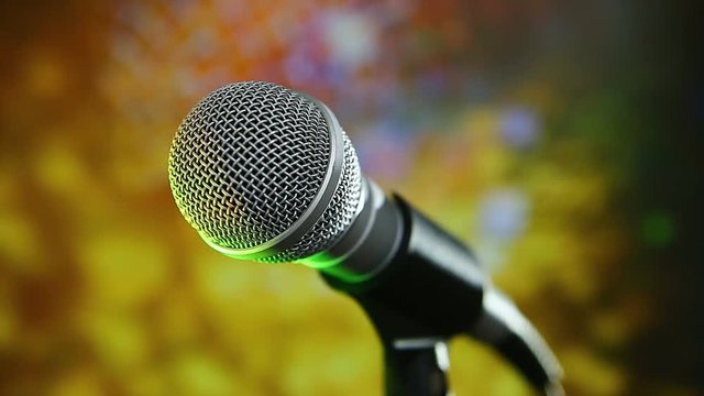 Microphone on stage with colorfull lighting and blurry background.