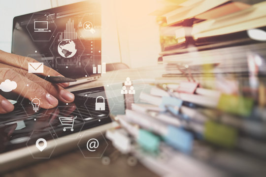 businessman working with laptop computer and digital tablet and book and document on wooden desk in modern office with virtual icons interface