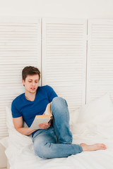 Man reading a book sitting on the bed