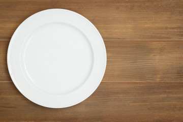 Top view of empty white dish on wooden background
