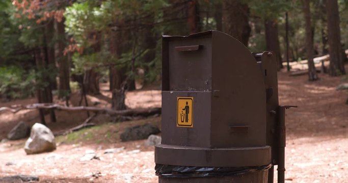 Female Goes To Trash Can And Throws Something Away In Nature.
