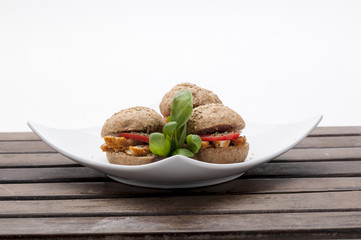 mini chicken sandwich, tomato, basil, olive on white plate for catering, events and party