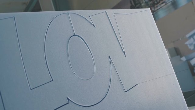 Close up: Cutting plastic foam. Automatic cutting of expanded polystyrene (foam plastic). The process of creating volumetric figures of foam plastic. Cutting out volumetric letters of foam plastic.