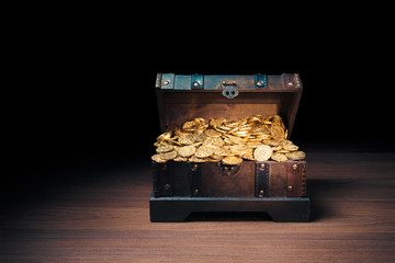 Open treasure chest with gold coins on a dark background