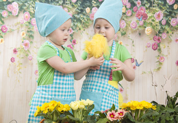 Two little adorable little girls play with yellow chicks