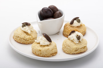 Elaborate canapes meat pies black olives presented in white plate with brown wooden tablecloth for events catering parties weddings