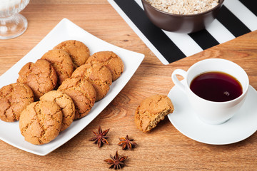 Plate of delicious homemade oatmeal cookies and a cup of black tea on the table