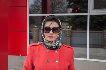 the girl in the red coat with old suitcase near the train station.