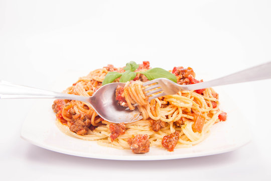 Spaghetti bolognese being eaten with a fork and spoon