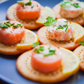 Salmon Canapes Appetizer on crackers with fresh herbs.