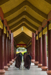 Monks on the way to prayer in a hallway with arched ceilings and columns