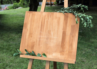 Wooden easel with a board. On the board written white paint - Welcome